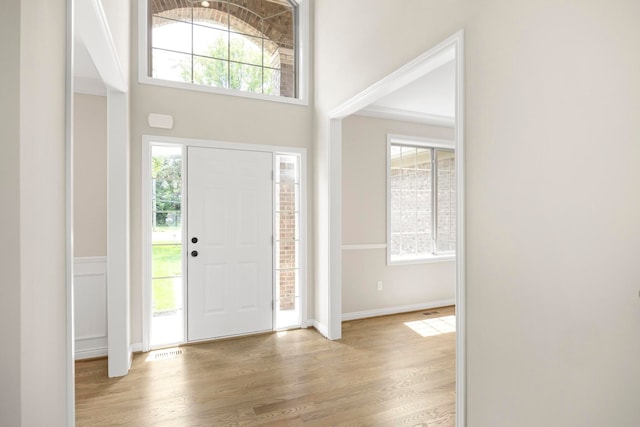 foyer featuring baseboards, visible vents, a healthy amount of sunlight, and light wood-type flooring