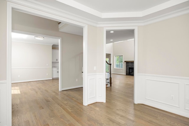 spare room featuring stairs, wainscoting, ornamental molding, and light wood finished floors