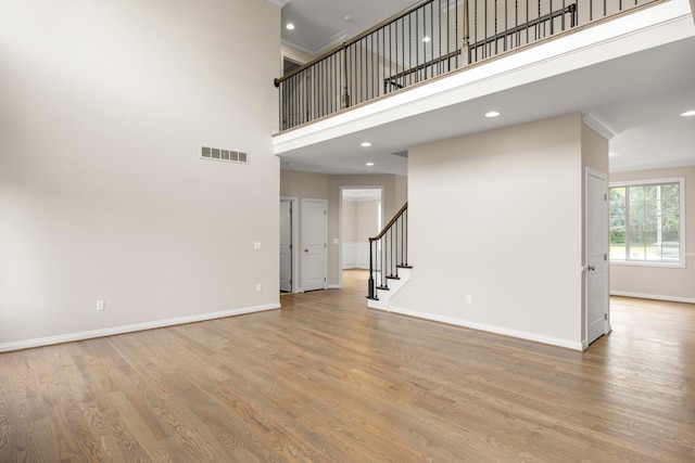 unfurnished living room featuring baseboards, stairs, wood finished floors, and visible vents