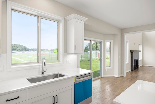 kitchen with a sink, light wood-type flooring, white cabinetry, and dishwasher