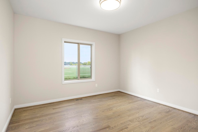 empty room with baseboards, light wood-type flooring, and visible vents