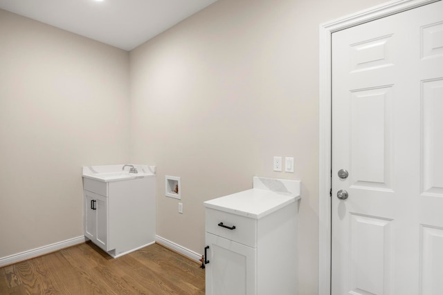 washroom featuring light wood-type flooring, hookup for a washing machine, cabinet space, and baseboards