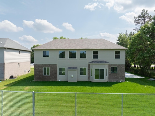 rear view of house featuring brick siding, a fenced backyard, and a lawn