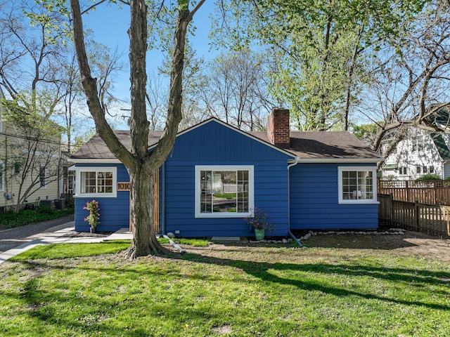 view of front of home with fence, a chimney, roof with shingles, and a front yard