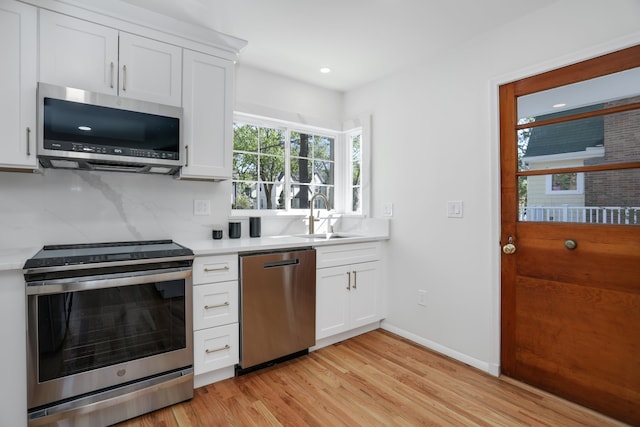 kitchen featuring light countertops, a sink, light wood finished floors, and stainless steel appliances