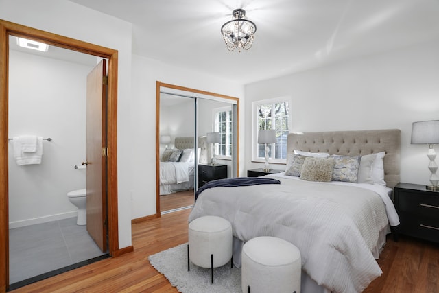 bedroom with a closet, baseboards, wood finished floors, and an inviting chandelier