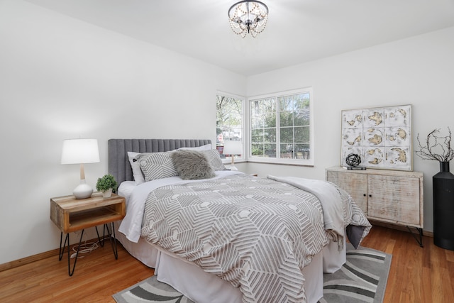 bedroom featuring baseboards, wood finished floors, and a chandelier