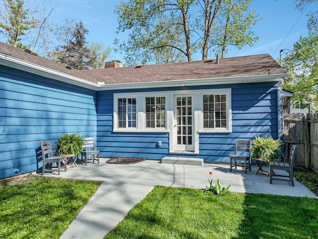 rear view of property featuring fence, a chimney, a lawn, and a patio area