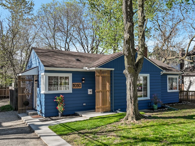 view of front of property with a chimney, a gate, fence, a front lawn, and a shingled roof