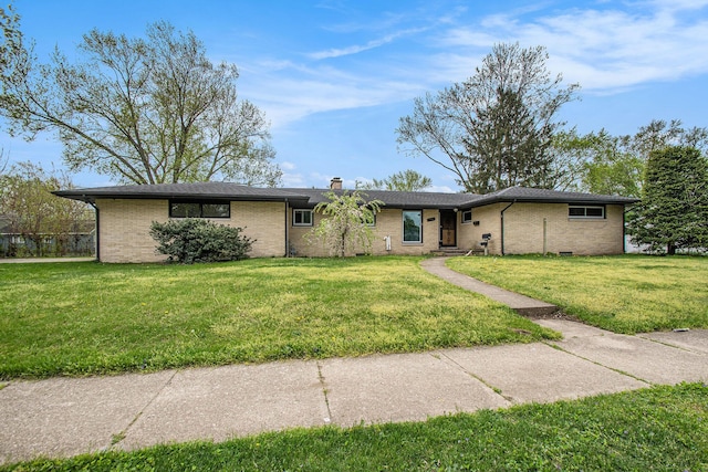 single story home featuring brick siding, a chimney, and a front yard