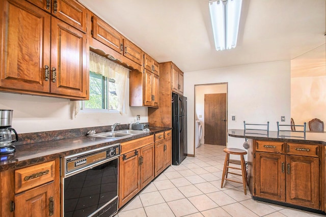 kitchen with a sink, washer / dryer, black appliances, and dark countertops