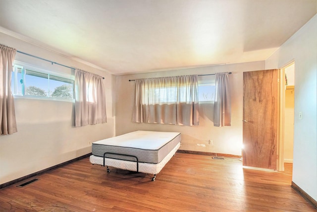bedroom featuring visible vents, baseboards, and wood finished floors