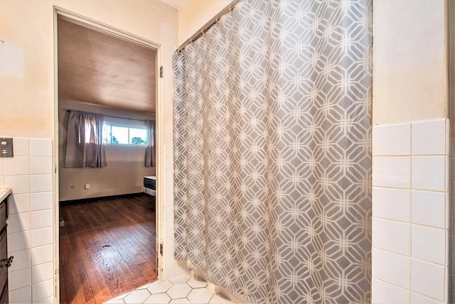bathroom with hardwood / wood-style floors, tile walls, curtained shower, and vanity