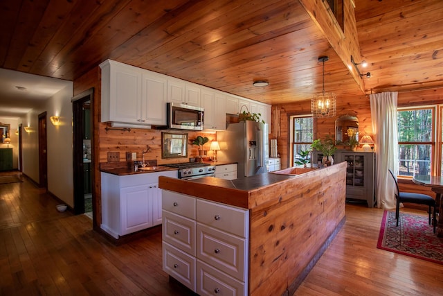 kitchen with white cabinets, dark wood finished floors, a center island, stainless steel appliances, and wooden ceiling