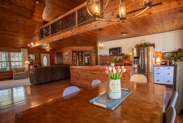 dining room with a high ceiling, an inviting chandelier, wood walls, wood finished floors, and wood ceiling