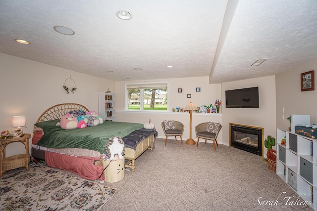 carpeted bedroom featuring a glass covered fireplace, baseboards, recessed lighting, and a textured ceiling