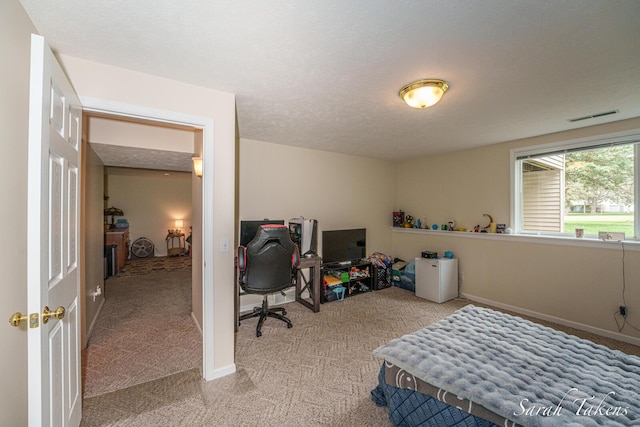bedroom with visible vents, a textured ceiling, baseboards, and light carpet
