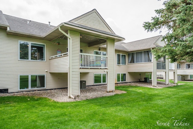 rear view of property with cooling unit, a yard, and a balcony