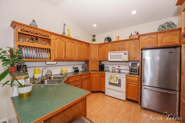kitchen featuring a sink, decorative backsplash, white appliances, and light wood-style flooring