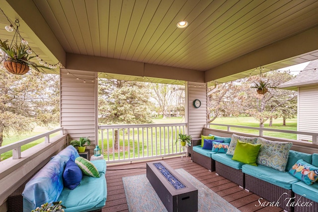 wooden deck featuring an outdoor living space with a fire pit