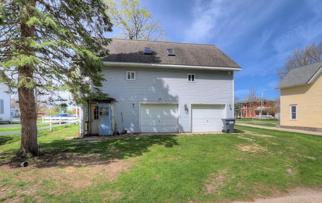 325 Pearl St, South Haven, MI 49090 - back of house featuring a lawn, an attached garage, fence, and roof with shingles