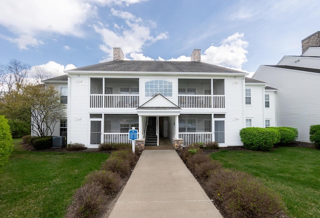 view of front of house with a chimney, a sunroom, and a front yard
