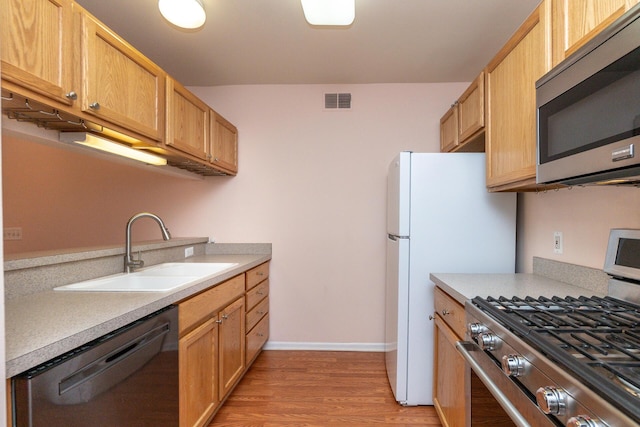 kitchen with visible vents, a sink, light countertops, light wood-style floors, and stainless steel appliances
