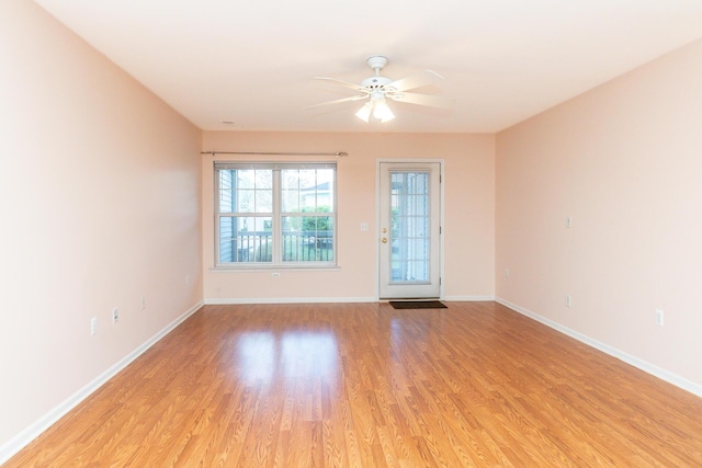 spare room featuring a ceiling fan, baseboards, and light wood-style floors