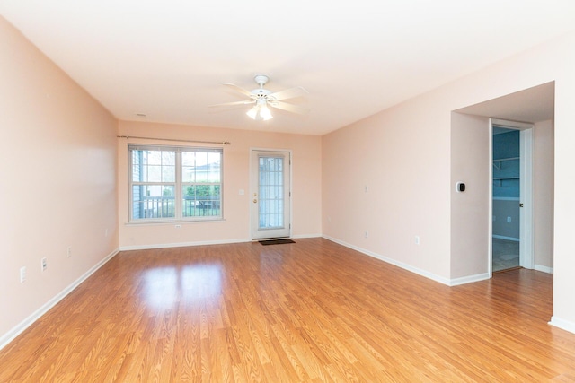 empty room featuring baseboards, ceiling fan, and light wood-style flooring