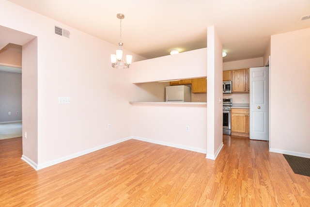 kitchen featuring hanging light fixtures, light wood finished floors, stainless steel appliances, baseboards, and visible vents