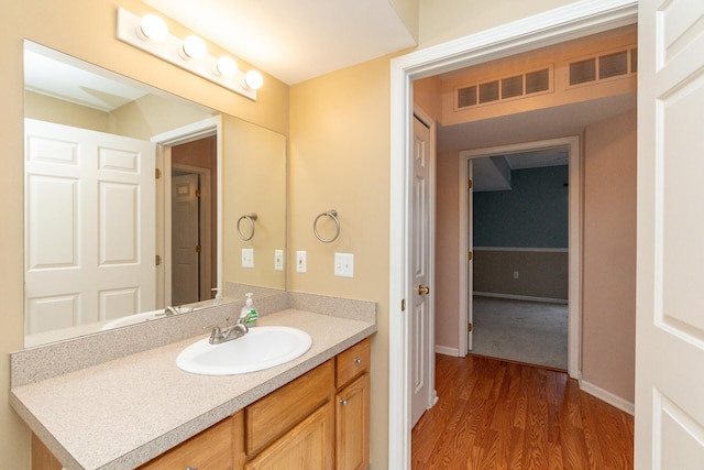 bathroom featuring vanity, baseboards, wood finished floors, and visible vents