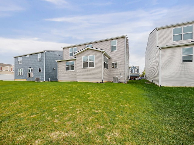 rear view of house featuring central AC unit and a yard