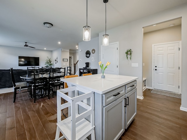 kitchen with dark wood finished floors, a kitchen island, ceiling fan, decorative light fixtures, and open floor plan