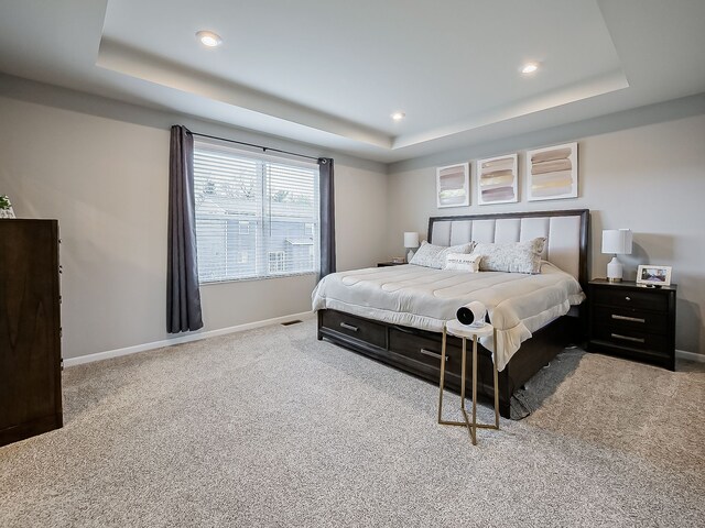 carpeted bedroom featuring a tray ceiling, baseboards, and recessed lighting
