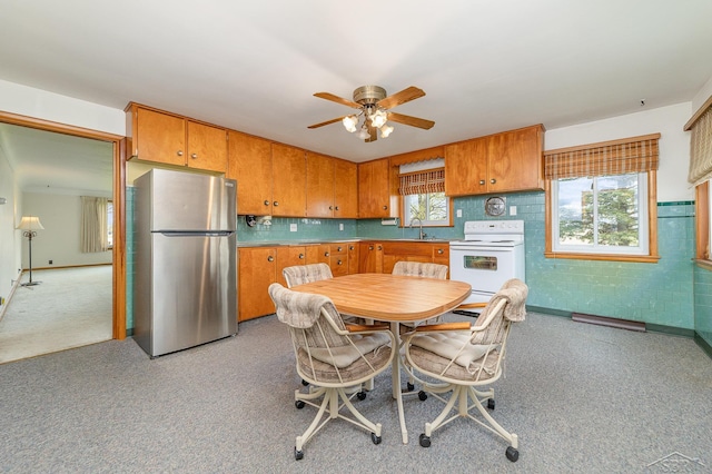 dining space featuring a ceiling fan, light colored carpet, and plenty of natural light