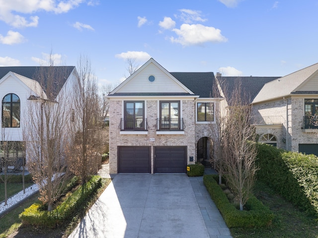 view of front of house featuring an attached garage, concrete driveway, brick siding, and a balcony