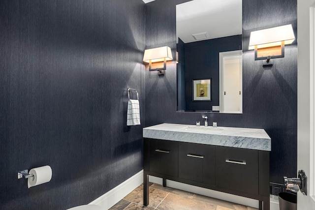 half bathroom with baseboards, vanity, and visible vents