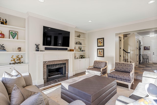 living area featuring a premium fireplace, built in features, stairs, recessed lighting, and ornamental molding