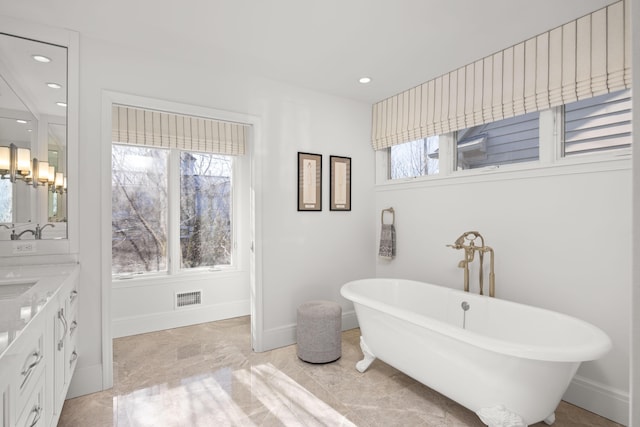 full bathroom featuring recessed lighting, a freestanding tub, visible vents, and vanity