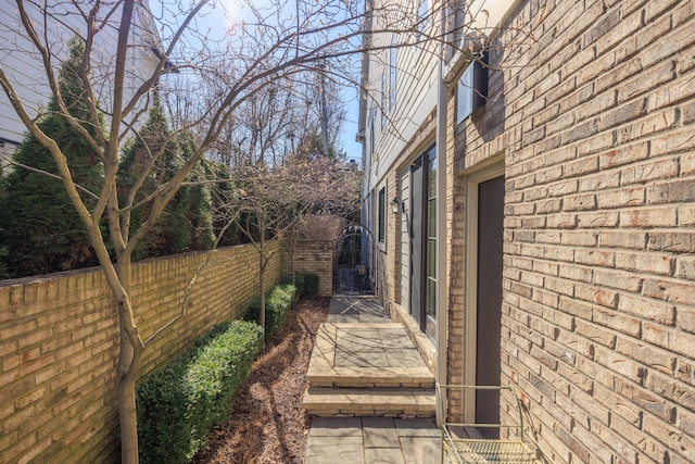 view of side of home with brick siding and fence