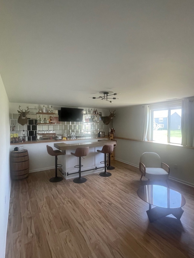 bar with baseboards, tasteful backsplash, and wood finished floors