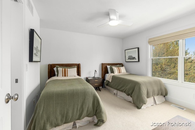 carpeted bedroom with a ceiling fan and visible vents