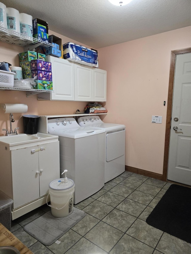 laundry room featuring a textured ceiling, cabinet space, light tile patterned floors, and washing machine and clothes dryer