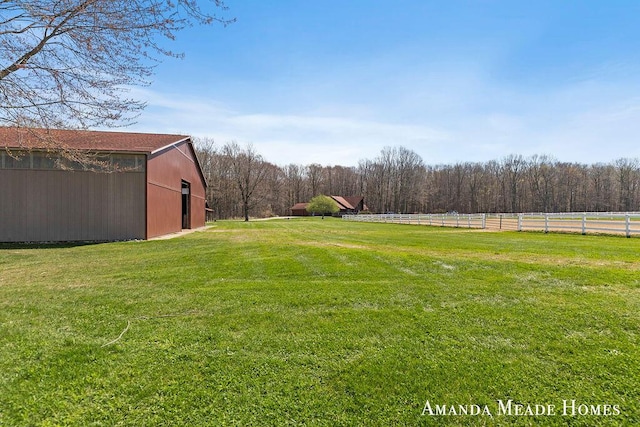 view of yard featuring fence, an outbuilding, and a forest view