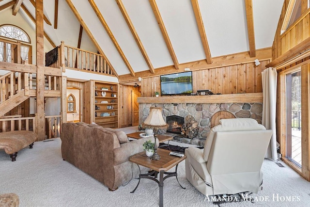 carpeted living area with wood walls, a fireplace, high vaulted ceiling, and beamed ceiling