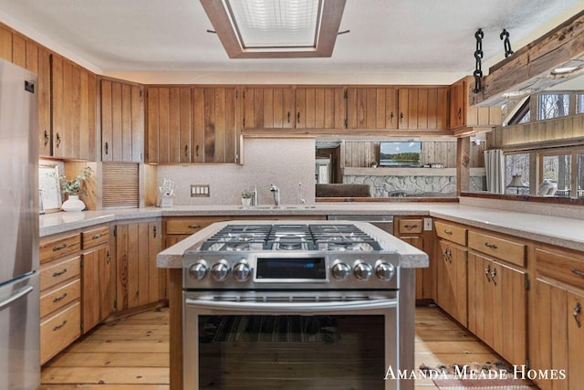 kitchen featuring light countertops, light wood-style flooring, appliances with stainless steel finishes, and tasteful backsplash