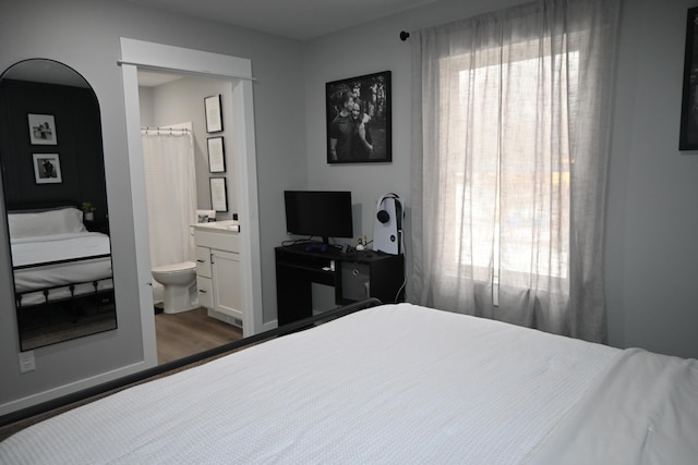 bedroom featuring ensuite bathroom and wood finished floors