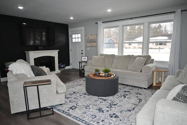 living room with baseboards, a fireplace with raised hearth, recessed lighting, and wood finished floors