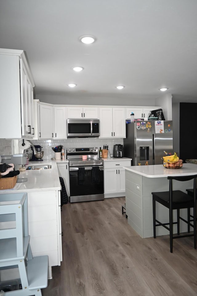 kitchen featuring appliances with stainless steel finishes, tasteful backsplash, a sink, light countertops, and white cabinets