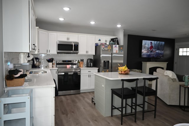 kitchen featuring appliances with stainless steel finishes, light countertops, white cabinets, dark wood-style floors, and open floor plan